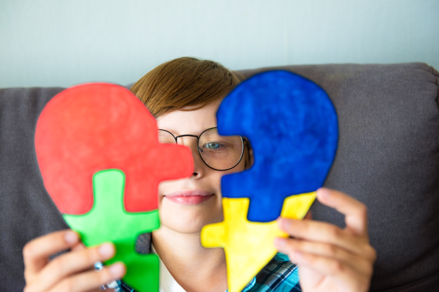 A student at Peterborough College holding colourful puzzle pieces, symbolising autism awareness and learning strategies, as part of the Autism and Learning Challenges course in the Health and Social Care department.